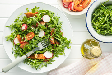 Fresh arugula salad with radishes, tomatoes and red peppers.