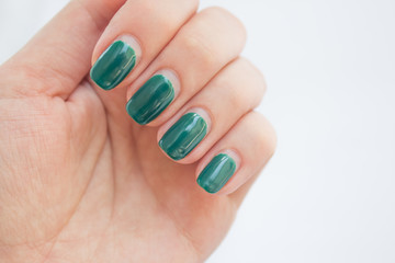 Damaged female nail with green manicure. Peeled off gel polish with nails. Home manicure concept