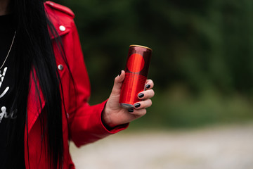 Woman in red leather jacket drinking cool soda cola drink from red can in hand. Woman drinking ,...