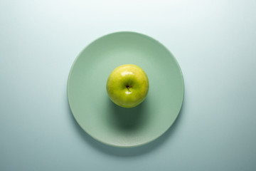 Fresh green apple on a turquoise plate