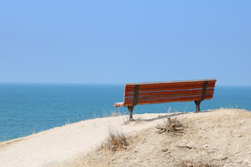 Fototapeta premium Lonely red painted bench with nice view on the Mediterranean Sea, Ashkelon, Israel. Low key filter