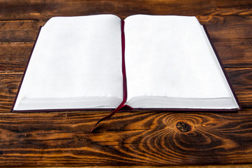 open book on a wooden background. holy bible on the table. notepad pages on the floor	