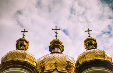 Fototapeta na wymiar White Orthodox Church with big golden domes on a cloudy day
