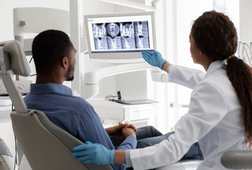Obraz premium Female dentist pointing at screen with xray picture
