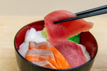 海鮮丼のマグロの刺身を箸でつまんで持ち上げる