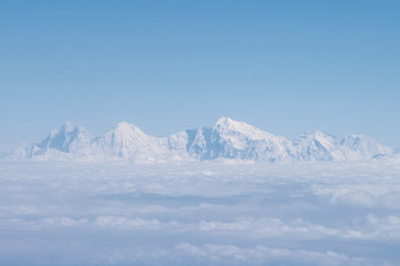 Cloudscape. Himalaya mountains rises above clouds. Clear blue sky. Photography made from window of airplane during flight to Nepal. Theme of beautiful landscapes.