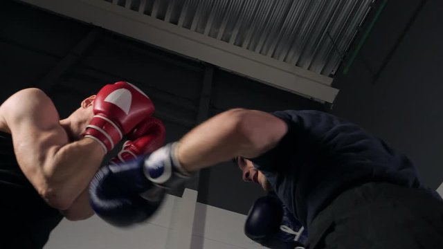 Low angle view of sportsmen fighting at boxing ring. Athletic men fighting on kickboxing match in health club. Sport, competition concept