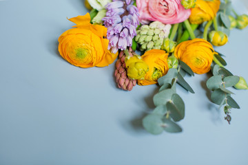 Beautiful bouquet with orange and pink ranunculus flowers, eucalyptus and hyacinth on a blue...