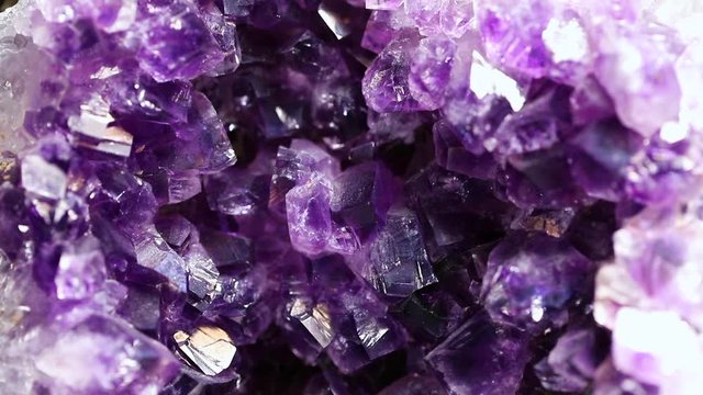 Iridescent light on an amethyst druzy stone. Macro footage.