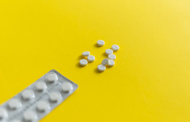 Top view on the pills in the package. White pills on yellow background. Medicine, medication,...
