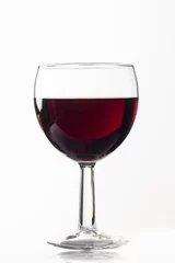 Fotobehang Side view of a glass glass of red wine on a white isolated background. Concept of wine preparation and tasting © Рустам Мухомедьяров