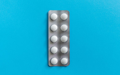 Top view on the pills in the package. White pills on blue background. Medicine, medication,...
