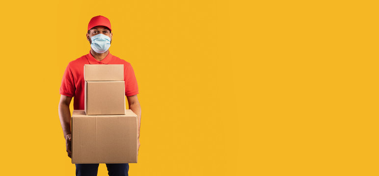 African Delivery Man Holding Boxes Wearing Mask, Yellow Background, Panorama