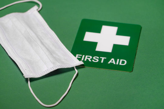 Medical mask and first aid sign on green background - Powered by Adobe