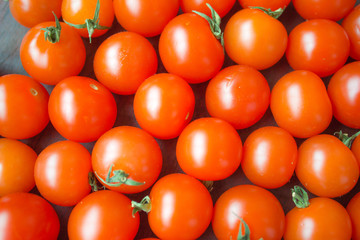 Red cherry tomatoes lie in the background, close close, on a Sunny day.