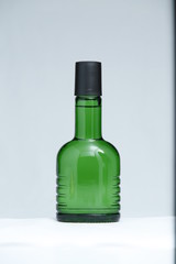 Beautiful green glass bottle with spray isolated on white background