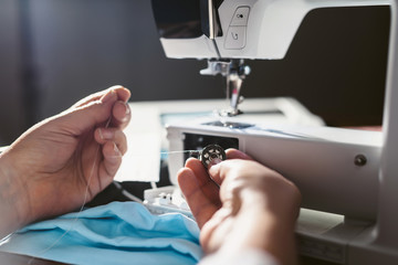 Close up sewing medical masks during the epidemic of the coronavirus Covid-19 pandemic. An elderly woman sews masks at home to protect against the spread of infection. Quarantine and self-isolation