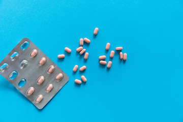 Top view on the pills removed from the pack. Pink pills on blue background. Medicine, medication,...