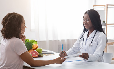 Obraz na płótnie Canvas Pretty doctor dietician giving female patient treatment plan
