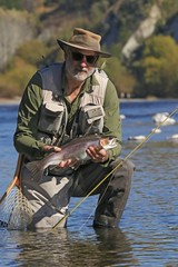 Fisherman with beard posing with trout in New Zealand river