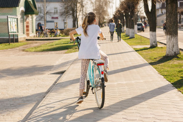 beautiful girl on a blue bicycle. girl rides a bicycle. summer holidays. spend time with benefit. female bicycle with basket