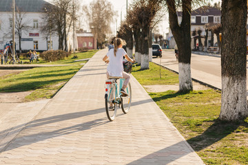 beautiful girl on a blue bicycle. girl rides a bicycle. summer holidays. spend time with benefit. female bicycle with basket