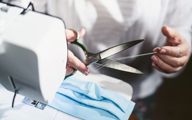 Close up sewing medical masks during the epidemic of the coronavirus Covid-19 pandemic. An elderly...