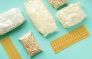 pearl barley, sugar, rice, oatmeal,spaghetti, semolina, beans in a package are on a mint background, the concept of purchasing and delivering food to your home