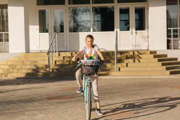 beautiful girl on a blue bicycle. girl rides a bicycle. summer holidays. spend time with benefit. female bicycle with basket