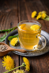 Herbal drink for liver detox, dandelion root tea in a glass cup decorated with fresh flowers