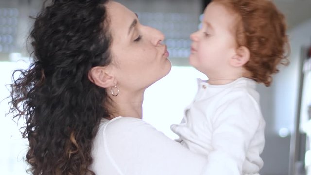 Slow motion 4K, two year old girl Beautiful Mother And her baby girl outdoors. Nature. Beauty Mom and her baby girl play together Kissing and hugging happy family. Mother's Day Joy.