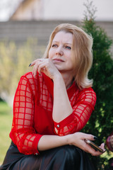 beautiful woman in red blouse. wrinkles on woman's face. blonde in a red blouse. a good looking mom