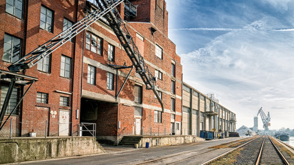 Fototapeta na wymiar A red industrial brick building on a port envelope with railroad tracks