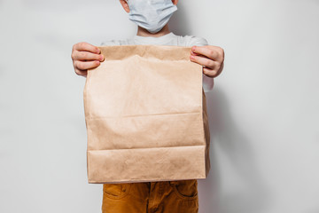 The courier guy holds in his hands a brown craft paper bag for the removal or delivery of goods and food on a white background. Place for advertising. delivery service concept - 345190036