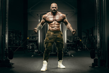 Fototapeta na wymiar Bodybuilder strong athletic man pumping up muscles
