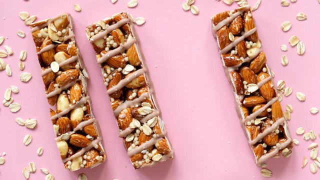 Almond granola bars on pink background. Female hand picking protein granola bar