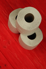 Three rolls of white toilet paper on red background with space for text. Deficit means of hygiene...