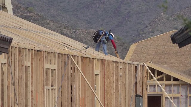 A Construction Worker Using a Nail Gun Building a House
