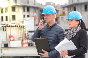 Construction manager in communication  on his walkie talkie while the architect is in inspection.