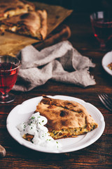 Slice of cabbage pie with sour cream sauce on white plate