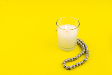 Ramadan Kareem Festival. Candle and rosary on yellow background. Happy ramadan hoilday. Copy space.