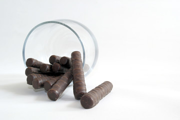 chocolate candies in the form of a tube in a glass on a white background