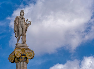 Fototapeta na wymiar Apollo white marble statue on Ionian style column under blue sky with some clouds, space for text