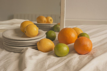 home /farmhouse detail of fresh lemons, limes, oranges, and vintage dishes over a white textured...
