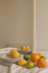 home /farmhouse detail of fresh lemons, limes, oranges, and vintage dishes over white textured sofa...