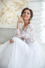Beautiful girl bride in a long lace dress with an elegant hairstyle.