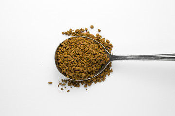 A spoonful of instant granulated coffee on a white background.
