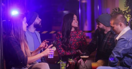 Multi-ethnic group of friends talking and drinking inside trendy bar