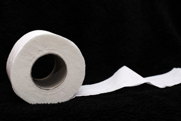 Toilet paper roll on a black background with copy space