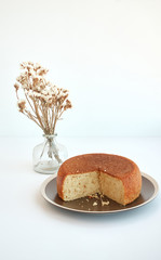 View of homemade pie on a brown plate and flowers in a vase isolated on white background. Vertical...